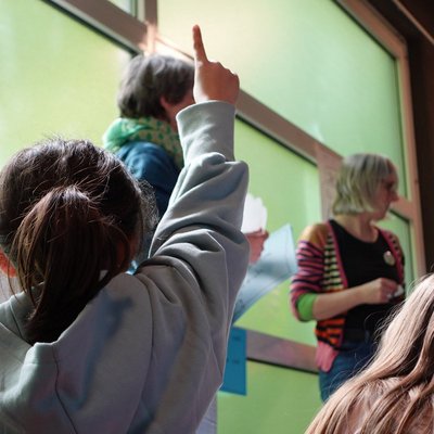 Kind von hinten, zeigt den Finger auf, weil es etwas sagen möchte