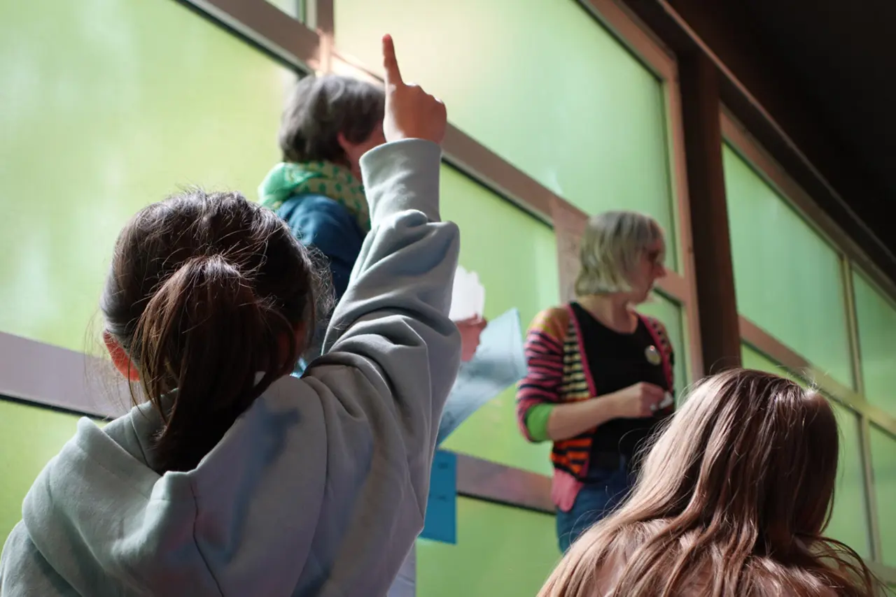Kind von hinten, zeigt den Finger auf, weil es etwas sagen möchte