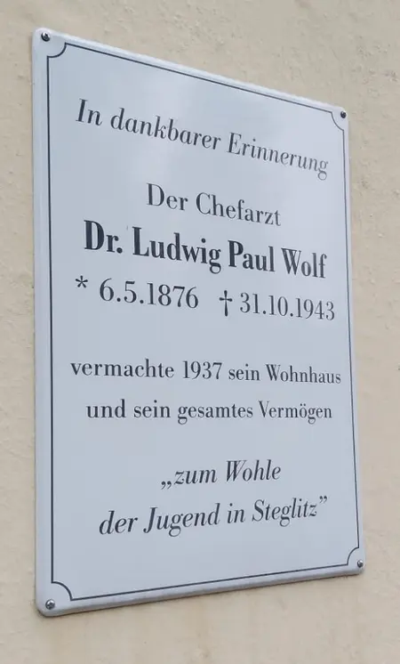 Die Gedenktafel (weiße emaillierte Blechtafel) wurde am 1.9.2006 durch Bezirksstadträtin Anke Otto enthüllt. Sie ist rechts neben dem Eingang am Gebäude des Kinder- und Jugendzentrums Dr. Wolf in der Geraer Straße 43 auf dem Putz befestigt.