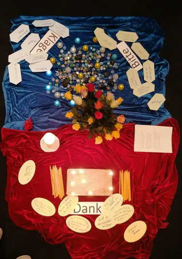 Gestaltete Mitte mit Tüchern, Blumen, Kerzen und handgeschriebenen Karten