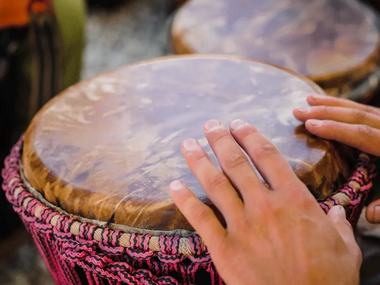 Zwei Hände trommeln auf einer Djembe