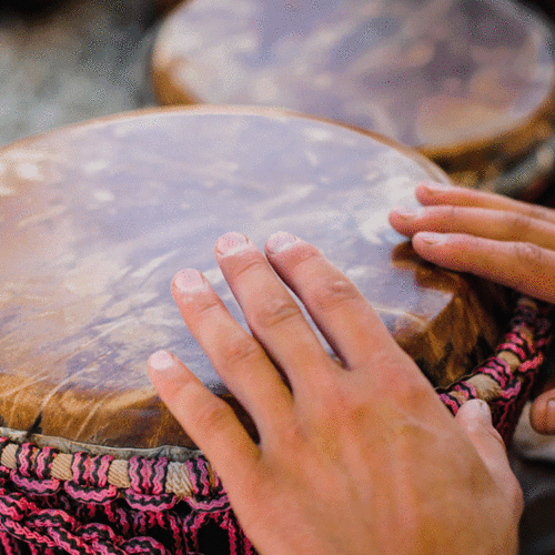 Zwei Hände trommeln auf einer Djembe
