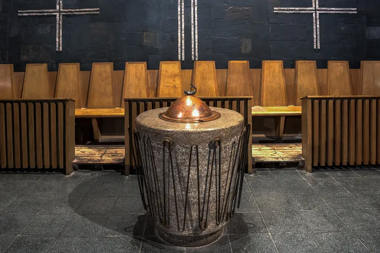 Taufstein aus poliertem Muschelkalkstein und mit Bronzestäben verziert in der Matthäuskirche in Berlin-Steglitz