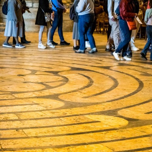 Labyrinth der Kathedrale von Chartres - am Rand sind die Beine einiger Menschen zu sehen, die das Labyrinth ablaufen.